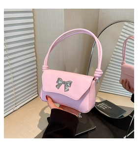Detailed macro view of the pink faux leather baguette bag featuring a silver bow buckle