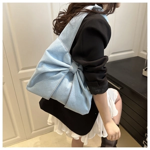 Detailed close-up of a light blue denim tote bag with a large stylish decorative bow
