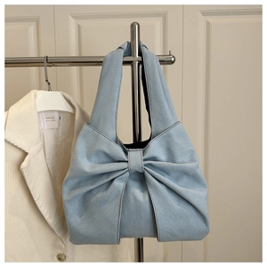 Blue denim tote bag with a large decorative bow and a spacious casual shoulder design