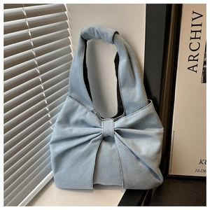 Detailed view of light blue denim tote bag with structural bow design and sturdy texture