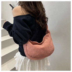 Detail of pink corduroy half-moon shoulder bag with ribbed texture worn by a model