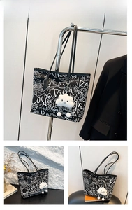 Detail of a black graffiti tote bag with plush cloud charm and hand-drawn patterns