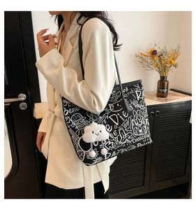 Detail of black graffiti tote bag with plush cloud charm and cartoon prints on shoulder