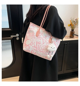 Close-up of white canvas tote bag with pink doodle art and plush cloud pendant