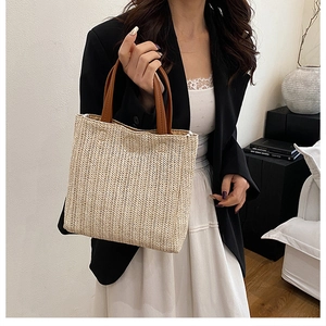 Detail of woven straw tote bag texture and high-quality brown leather double handles