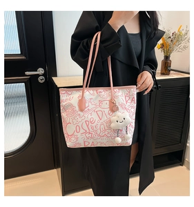 Detail of white graffiti tote bag with pink leather handles and plush cloud pendant charm
