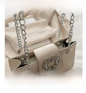 Detail of cream shoulder bag with rhinestone buckle and silver chunky chain strap
