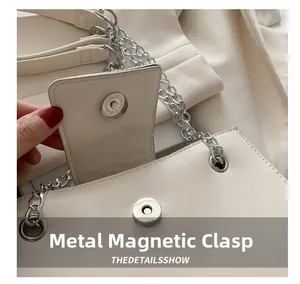 Close-up of a cream leather handbag featuring a silver magnetic metal clasp and chain