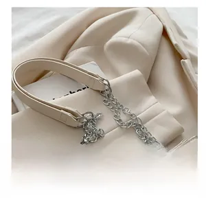 Detail of beige shoulder bag featuring silver chain strap and large horseshoe rhinestone buckle