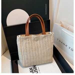 Detail of herringbone weave texture on ivory straw tote bag with brown leather handle