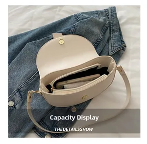 Interior capacity display of the cream half-moon saddle bag showing daily essentials