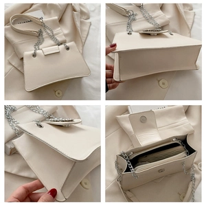 Detail view of cream shoulder bag showing leather texture, metal chain and inner compartments