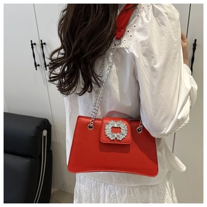 Detail of red shoulder bag featuring silver chain strap and large crystal square buckle