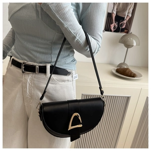 Vue détaillée d'un sac selle noir avec boucle triangle dorée porté par un mannequin