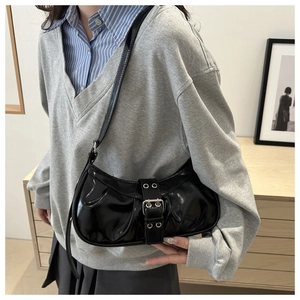 Detail shot of black patent leather hobo bag with eyelet buckle and wrinkled texture