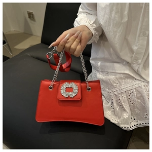 Detail of red hourglass handbag featuring a luxury crystal buckle and silver chain strap
