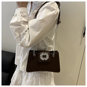 Detailed view of deep brown leather bag featuring a large rectangular rhinestone buckle