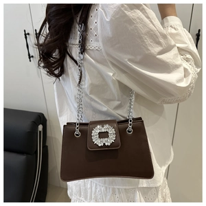 Close-up of a chocolate brown leather bag featuring a large sparkling crystal buckle