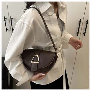 Dark brown matte leather saddle bag with a large golden horseshoe buckle on the flap