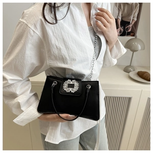 Detail of black leather handbag with rhinestone buckle and silver chain strap