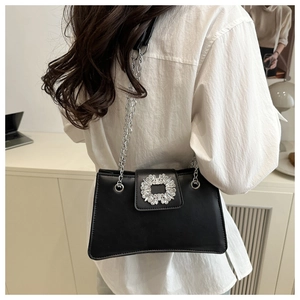 Close-up of elegant black shoulder bag with rhinestone square buckle and chain strap