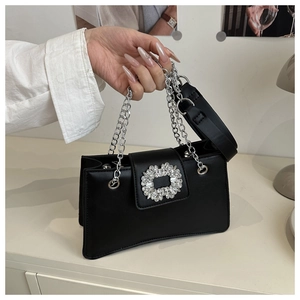Close-up of black leather bag featuring a large sparkling rhinestone buckle and silver chain
