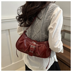 Detail view of burgundy glossy leather underarm bag with stylish pleats and silver buckle