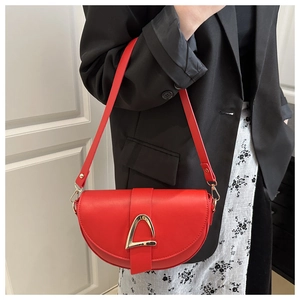 Detail of red saddle bag with gold triangle buckle worn over a black blazer
