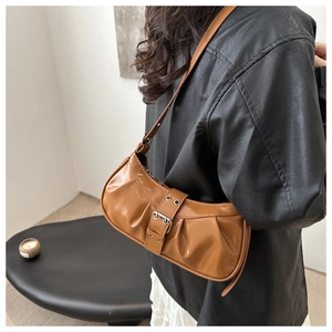 Close-up of caramel brown ruched underarm bag with metal buckle and rivet detail