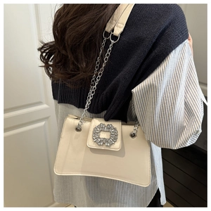 Detailed view of ivory shoulder bag with rhinestone buckle and silver chain strap