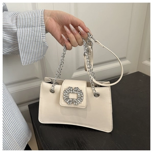 Detail of cream leather handbag with sparkling rhinestone buckle and silver chain strap