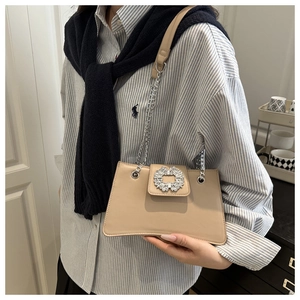 Close-up of elegant beige leather baguette bag featuring a luxury sparkling rhinestone buckle
