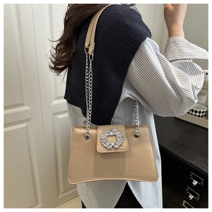 Detail of beige shoulder bag with sparkling rhinestone buckle and silver chain strap