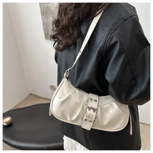 Close-up of off-white glossy leather half-moon bag with silver buckle and pleated detail
