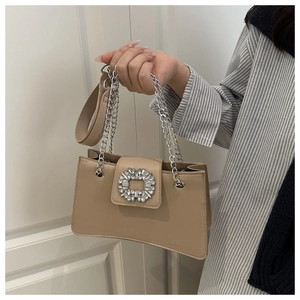 Detail of beige shoulder bag with sparkling rhinestone buckle and silver chain strap