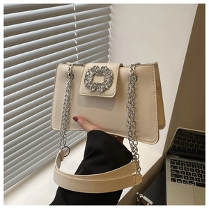 Close-up of beige leather shoulder bag featuring a luxurious rhinestone encrusted buckle