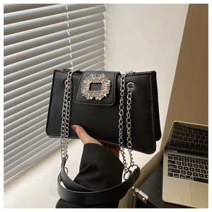 Close-up of sparkling rectangular crystal buckle and silver chain on black shoulder bag
