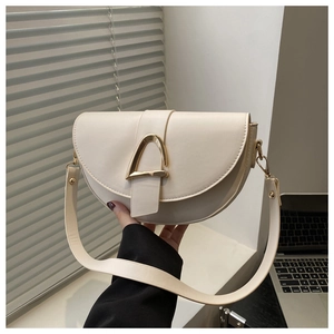 Gros plan sur le sac selle blanc crème montrant le cuir PU lisse et la boucle en D dorée