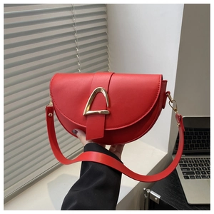 Détail d'un sac besace en cuir rouge avec boucle en métal doré et bandoulière longue