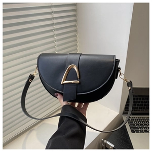 Détail d'un sac besace noir en similicuir avec boucle dorée et texture fine