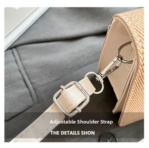 Detail of adjustable beige leather strap with silver metal buckle on yellow woven bag