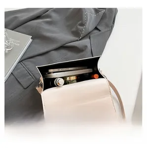 Interior view of beige glossy camera bag showing storage capacity for phone and lipstick
