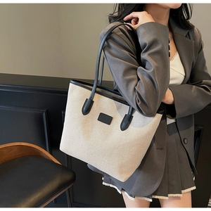Detail of the high-capacity canvas tote bag featuring black leather trim and shoulder straps