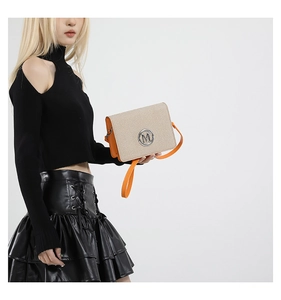 Detail of crossbody bag with beige weave, orange leather trim and metal M logo