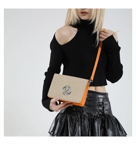 Detail of a chic crossbody bag with orange leather, woven lid, and silver M logo