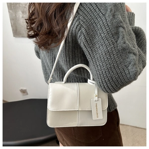 Detail view of cream white plaid tote bag featuring textured faux leather and tag