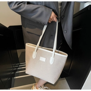 Detail of a large canvas tote bag with contrast faux leather trim for daily commuting