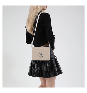 Detail of beige textured crossbody bag with silver M logo and matching shoulder strap