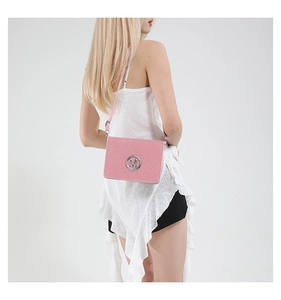 Close-up of pink crossbody bag with woven texture and silver M logo on model