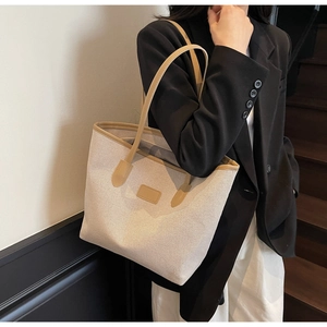 Minimalist canvas tote bag with leather trim shown on shoulder in a modern indoor setting